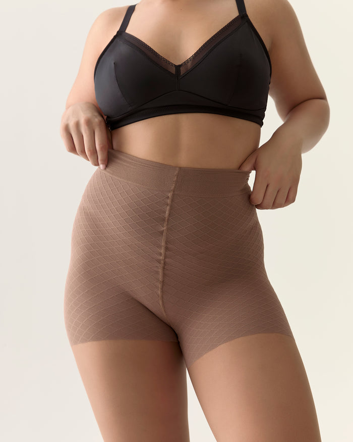 Close-up of the natural smoothing waistband on the Back Vine Sheer Tights in Coffee, styled with a black bra.