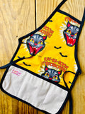 Amanda Bright Designs gold and black cat children’s apron with black cat fireworks screaming cat-face and bats flying. The apron has black trim, natural canvas front pockets, and black neck and waist ties
