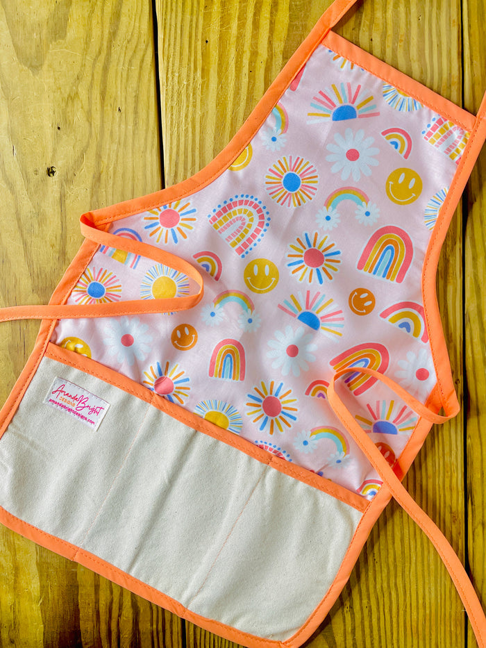 Amanda Bright Designs Children's apron with colorful rainbows, smiley faces, sunshine with peach strings