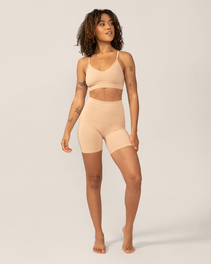 Woman wearing a beige shapewear set on a plain background