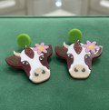 Amanda Bright Designs brown and white cow-shaped earrings with pink flower and green acrylic stud earrings