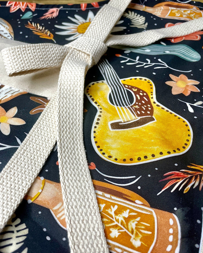Amanda Bright Designs Delilah Apron with colorful western guitar cactus cowboy hat sunflower pattern on black background