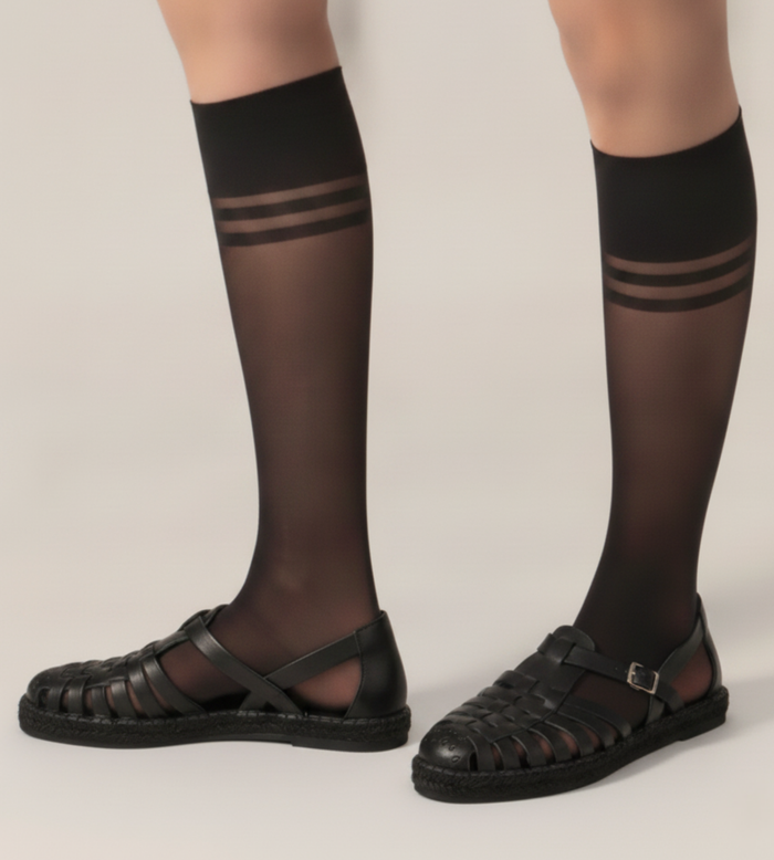 Black knee-high socks with striped design worn by a person on a plain background