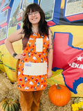 Amanda Bright Designs halloween apron model featuring dogs in costumes on orange backgroun