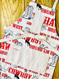 Amanda Bright Designs Cowboy-themed aprons with text and graphics Jane Long Mother of Texas boots, steer, sheriff badge, stars, horseshoes, roping cowboy, horse