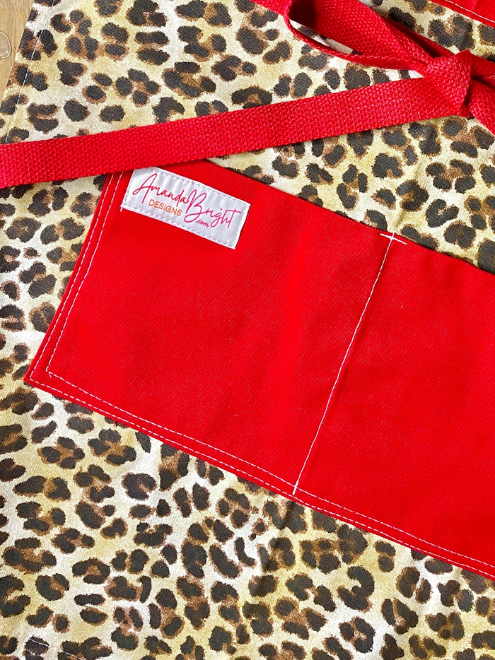 Kat Retro Designer Midcentury Apron Leopard 1950s Glamorous Animal Print Red Strings and Pockets on model