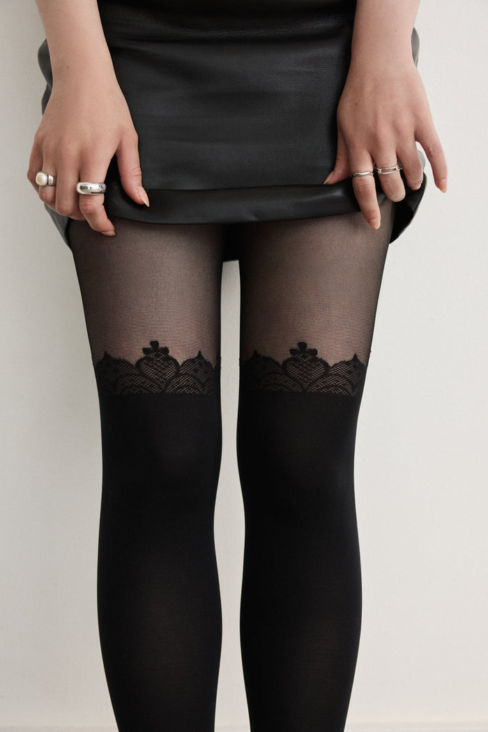 Close-up of Rachel's Lace Crown Over-the-Knee Tights in Black, showing the lace pattern at the top of the thigh.