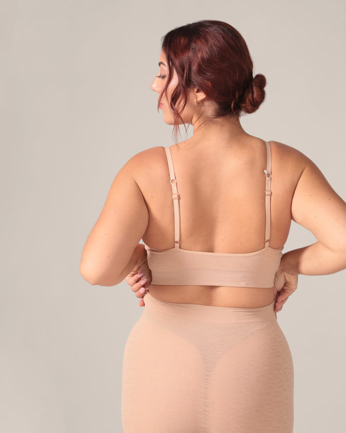 Woman wearing a beige compression garment against a plain background