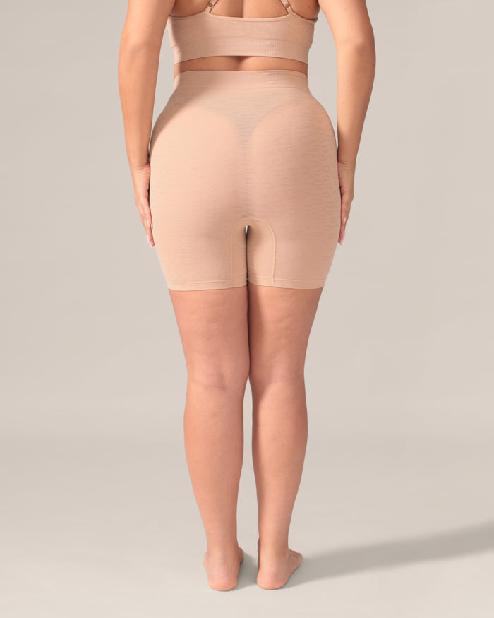 Person wearing beige shapewear shorts on a plain background