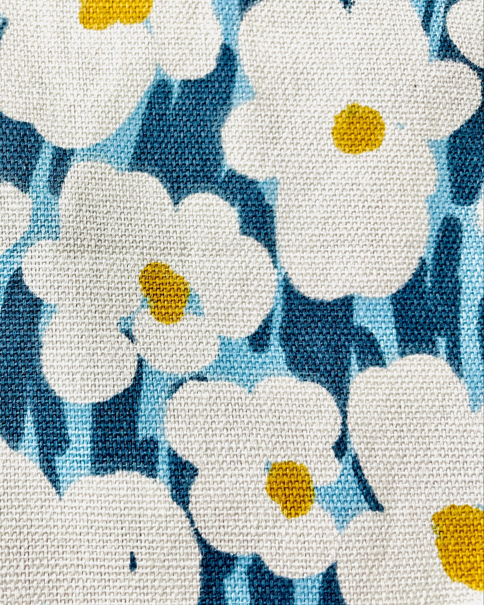 Amanda Bright Designs Bold White Floral Apron with Golden Centers on a bright blue and navy background