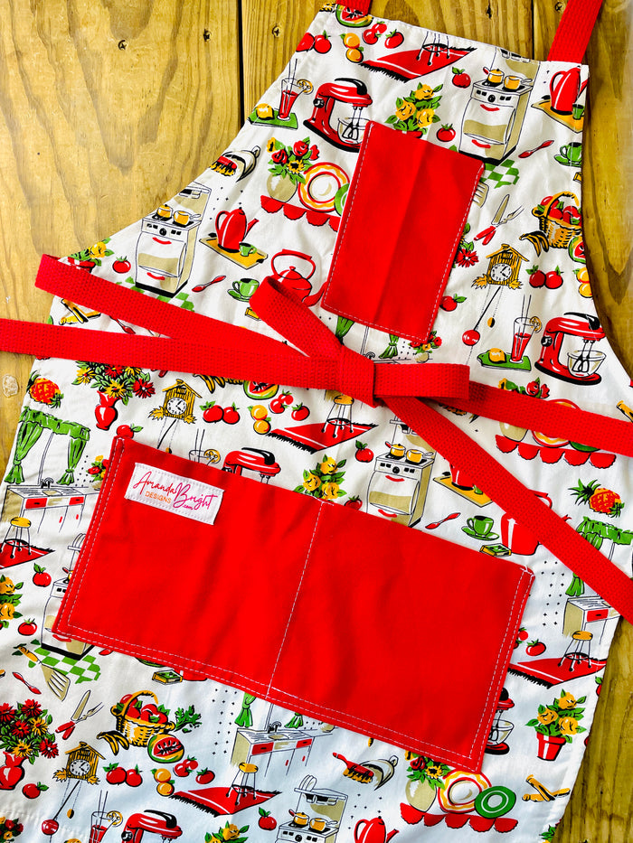 Amanda Bright Designs Lucille apron 1950s kitchen appliances pattern in red and green with red pockets and strings