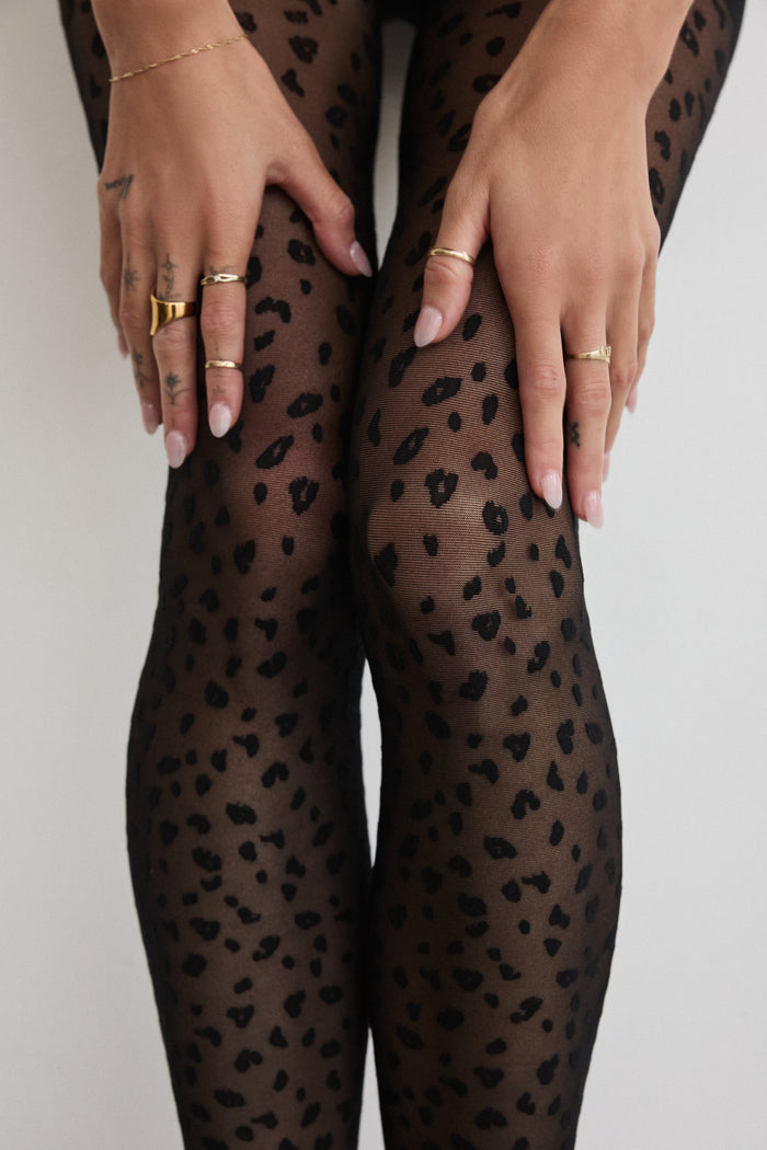 Close-up of Rachel's Mini Leopard Tights in Black, showing the leopard print pattern from thigh to knee.