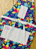 Amanda Bright Designs Nikki multicolored tropical Florida Hawaii floral apron with pink flamingo patterns on a blue background, featuring cotton strings and canvas pockets