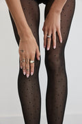 Hands adjusting the Polka Dot Tights in Black at the thigh, showing the dot pattern up close.