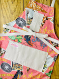 Amanda Bright Design colorful cotton apron with cowboy-themed design let ‘er buck saddle up buckle cowboy boot cactus postcard western