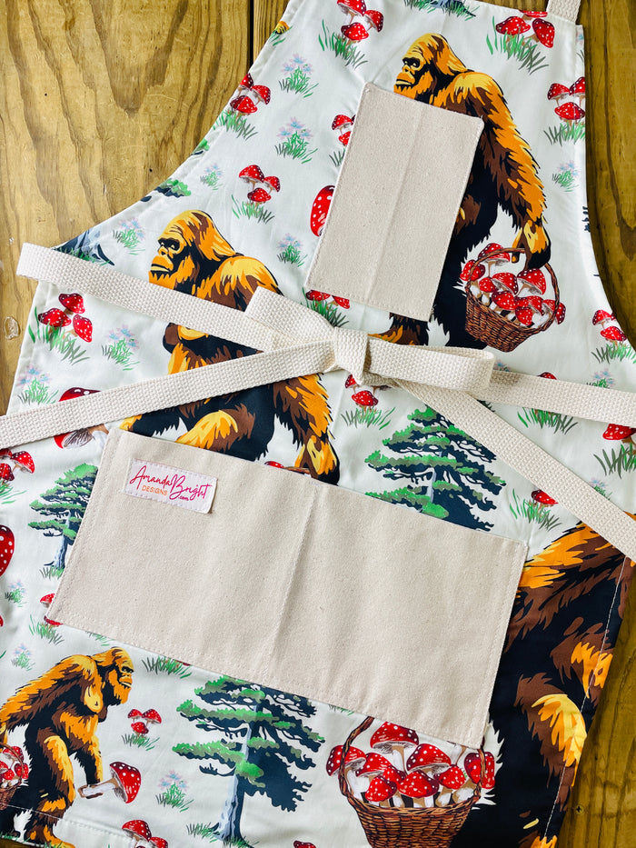 Apron with bigfoot carrying basket of mushrooms Amanda bright designs