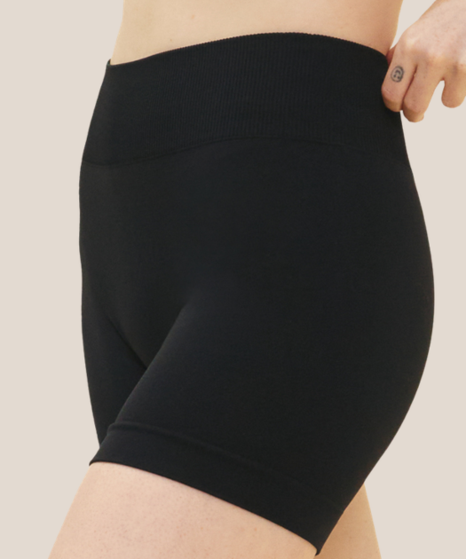 Black biker shorts being worn on a beige background