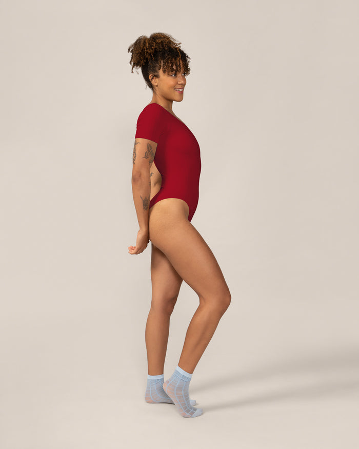 Person wearing a red bodysuit on a plain background