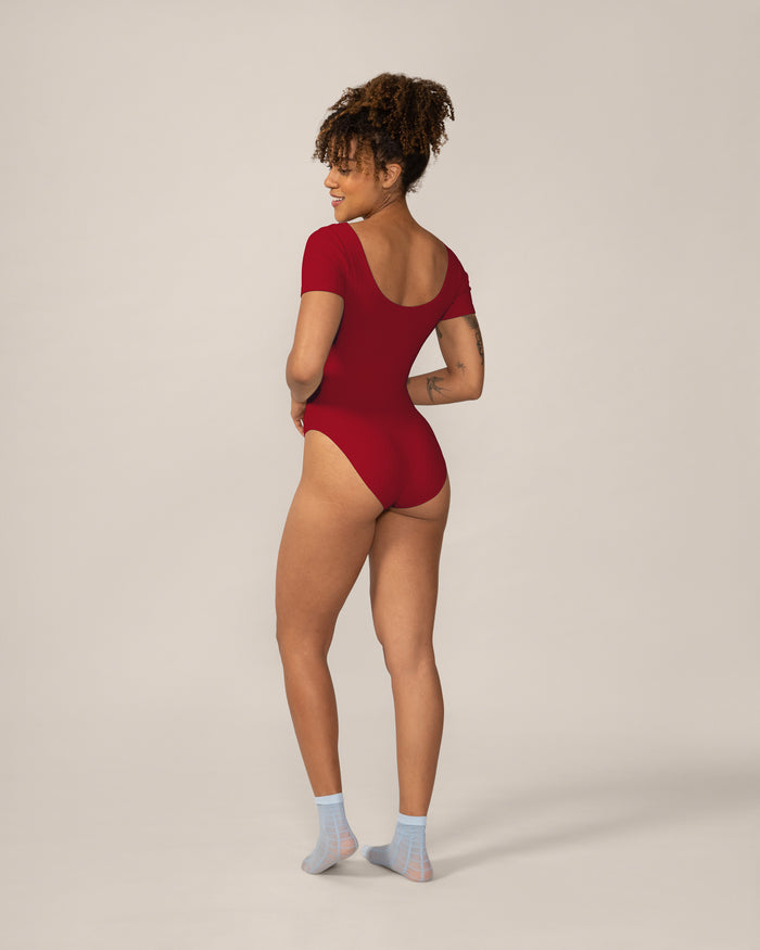 Person wearing a red bodysuit on a plain background