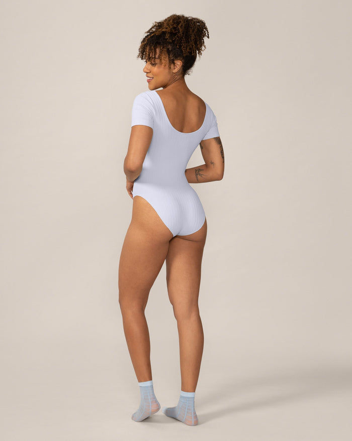 Woman wearing a light blue bodysuit on a beige background