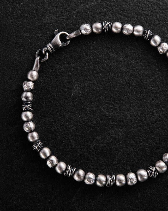 Silver beaded bracelet on a black background