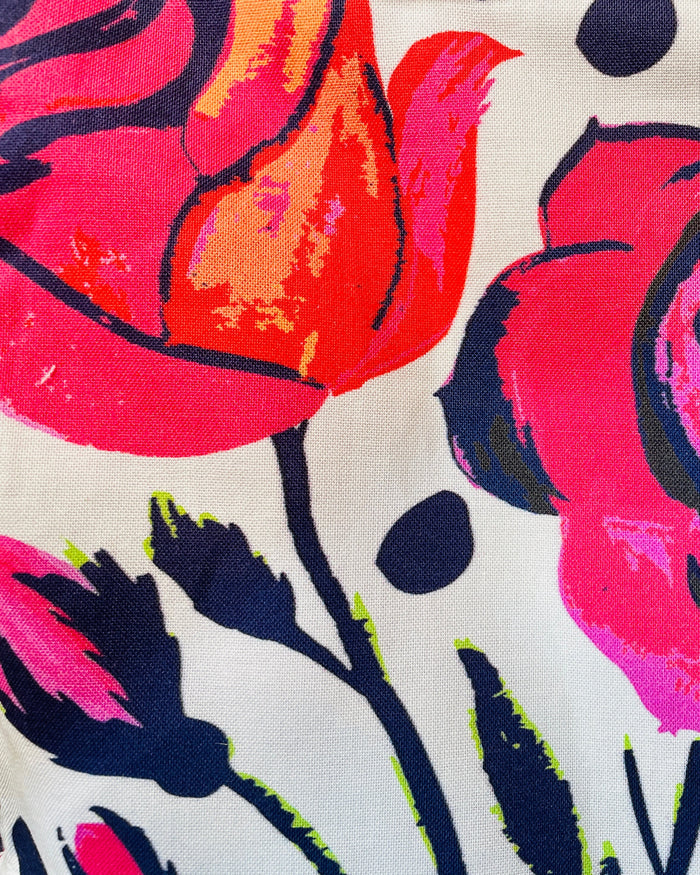 Amanda Bright Designs apron pattern Close-up of a fabric with colorful floral pattern featuring pink, red, and black roses on a white background
