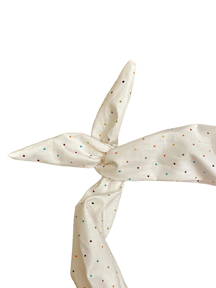 Amanda Bright Designs ivory fabric headband with small multicolored polka dots, tied in a knot