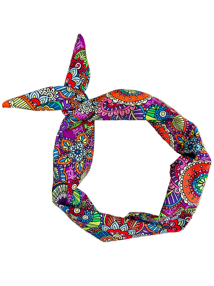 A knotted fabric headband with a vibrant, multicolored paisley and floral pattern by Amanda Bright Designs