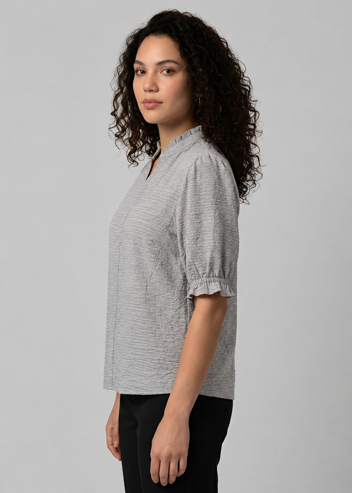Flurr Woman wearing a textured ruffle collar top with short ruffle sleeves, styled with black trousers for a polished officewear look